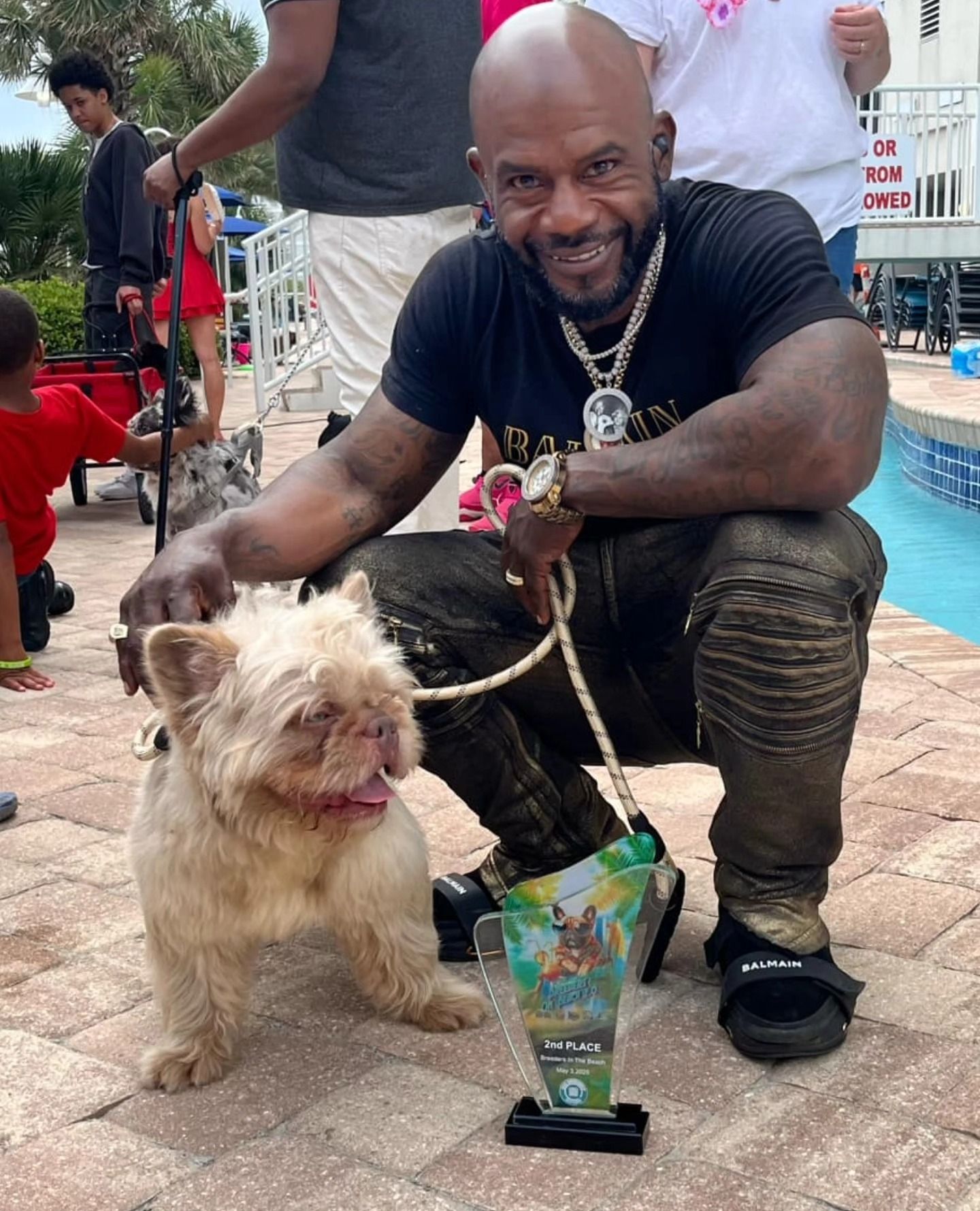 A handler with an Itty Bitty Kennels French Bulldog and its award at Breeders on the Beach